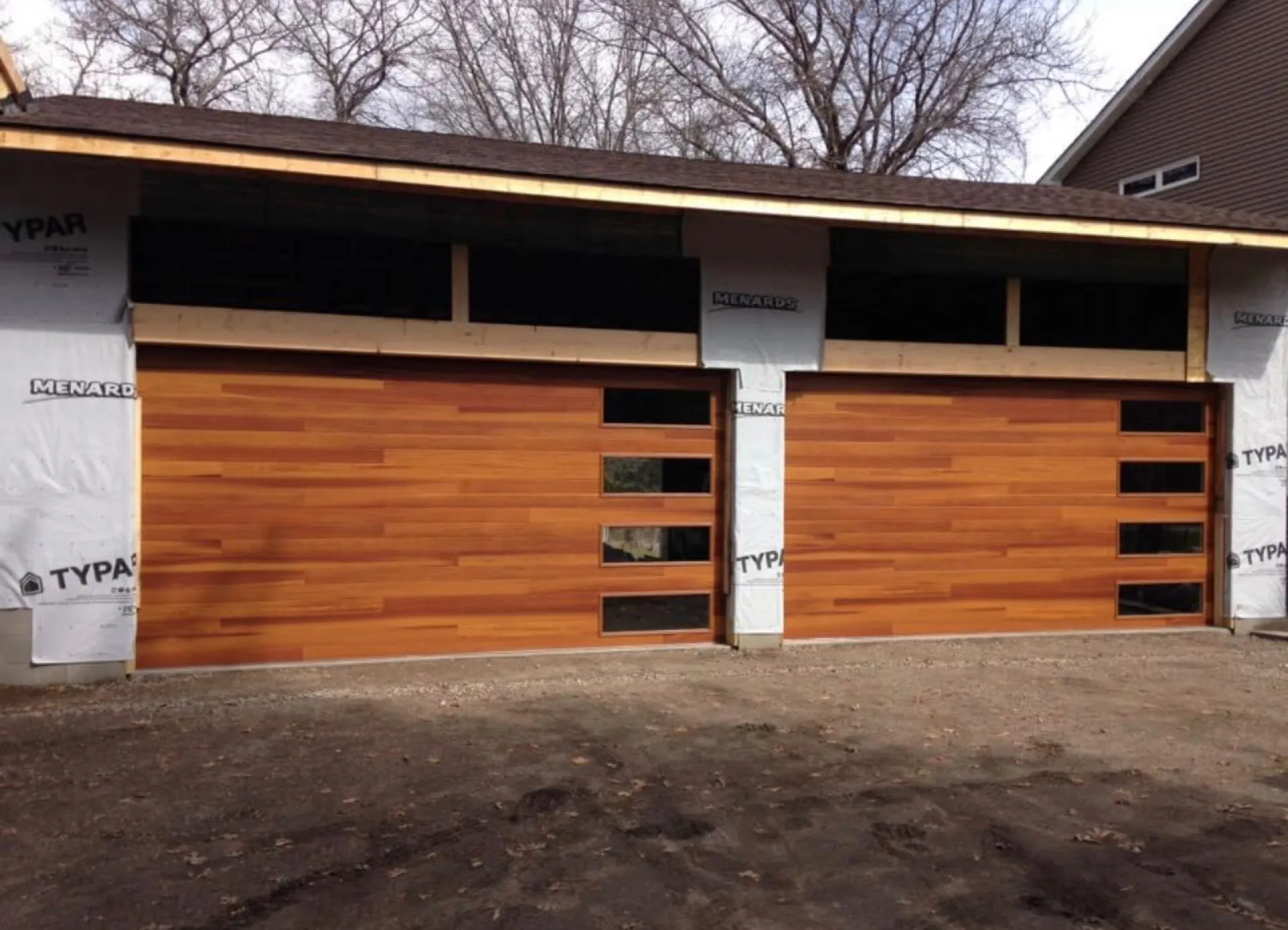 Twin cedar-wood overhead doors installed on a new-construction garage