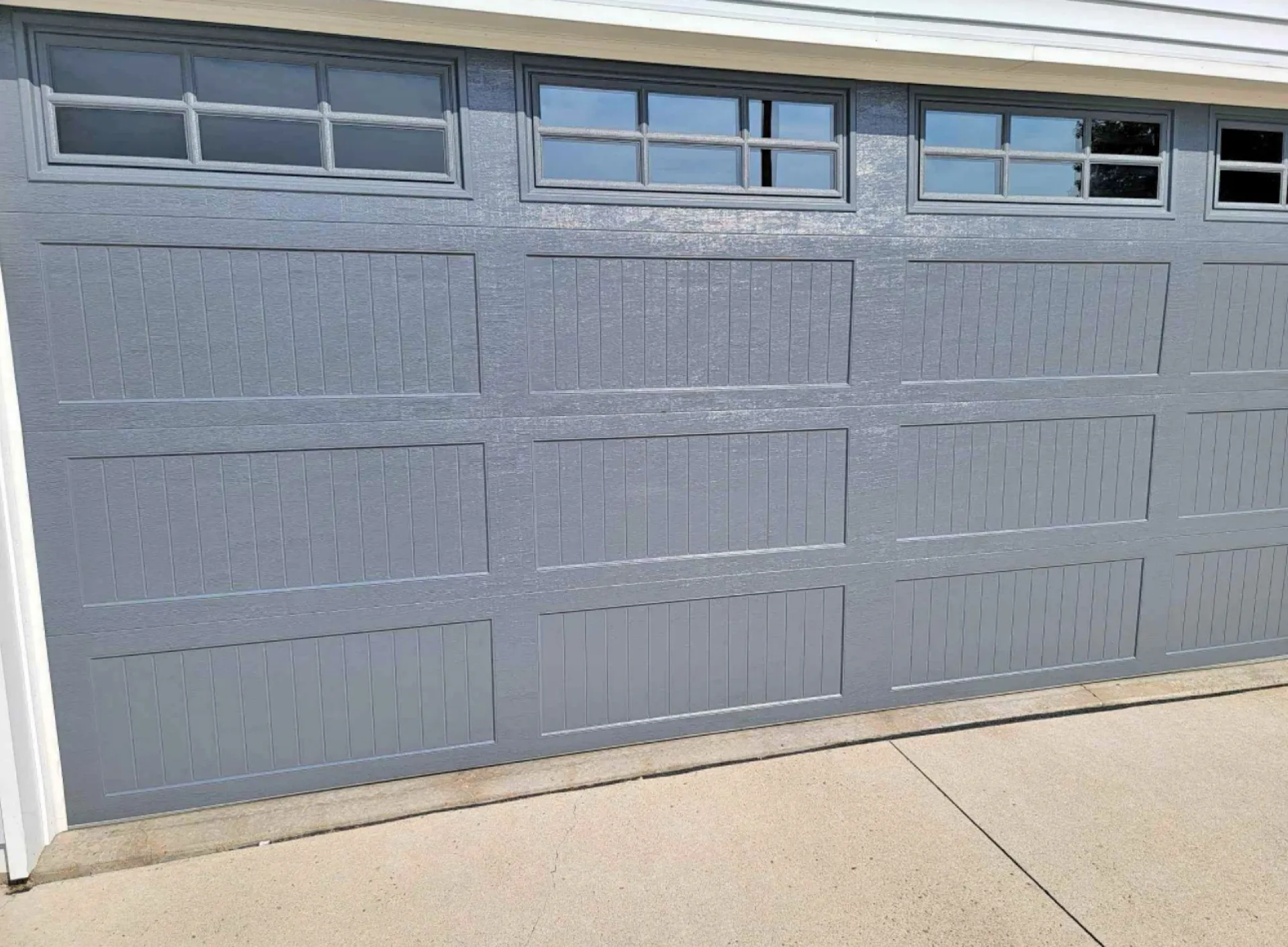 Gray carriage garage doors with top row windows on a suburban home