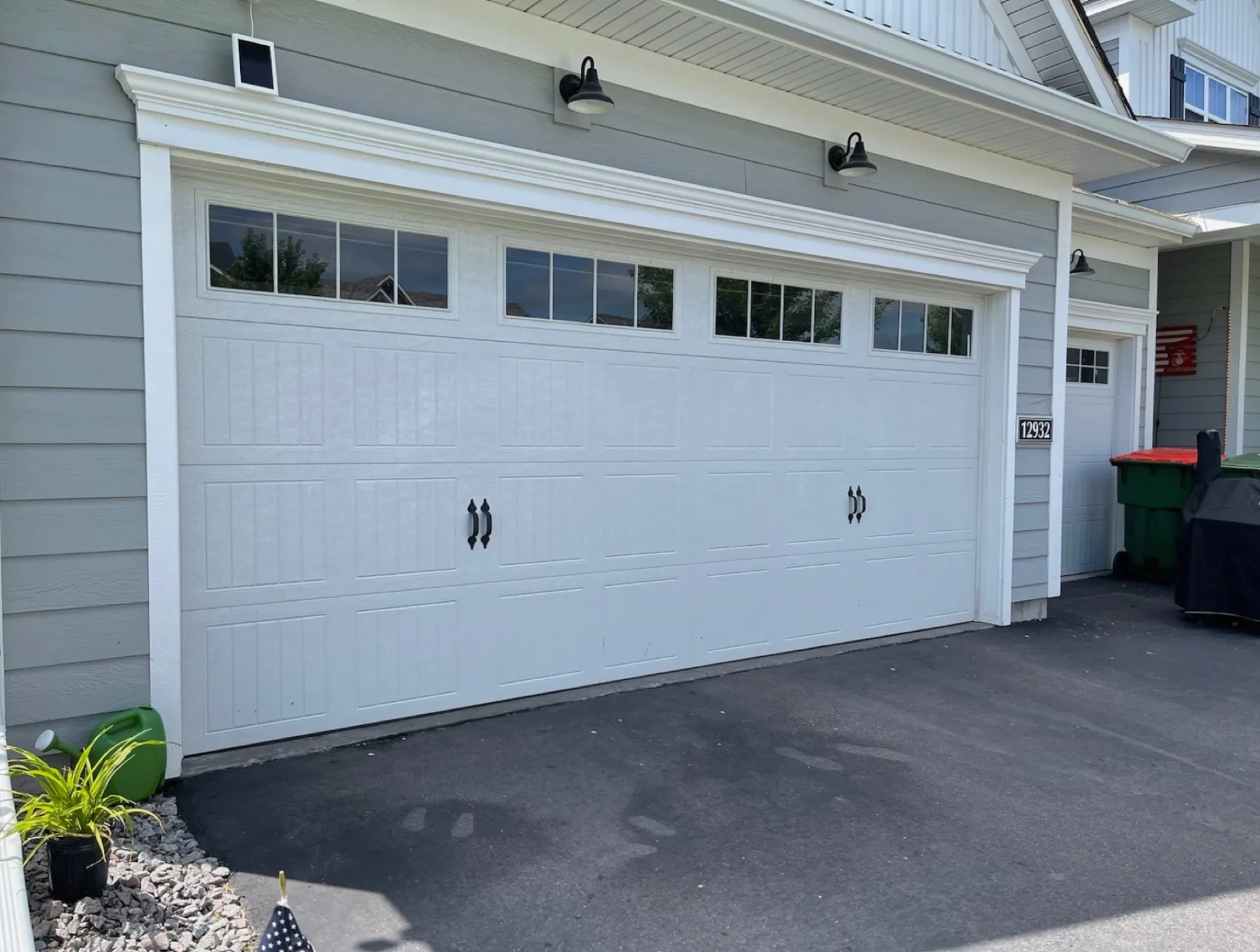 Clean white carriage garage door with decorative handles and top row windows