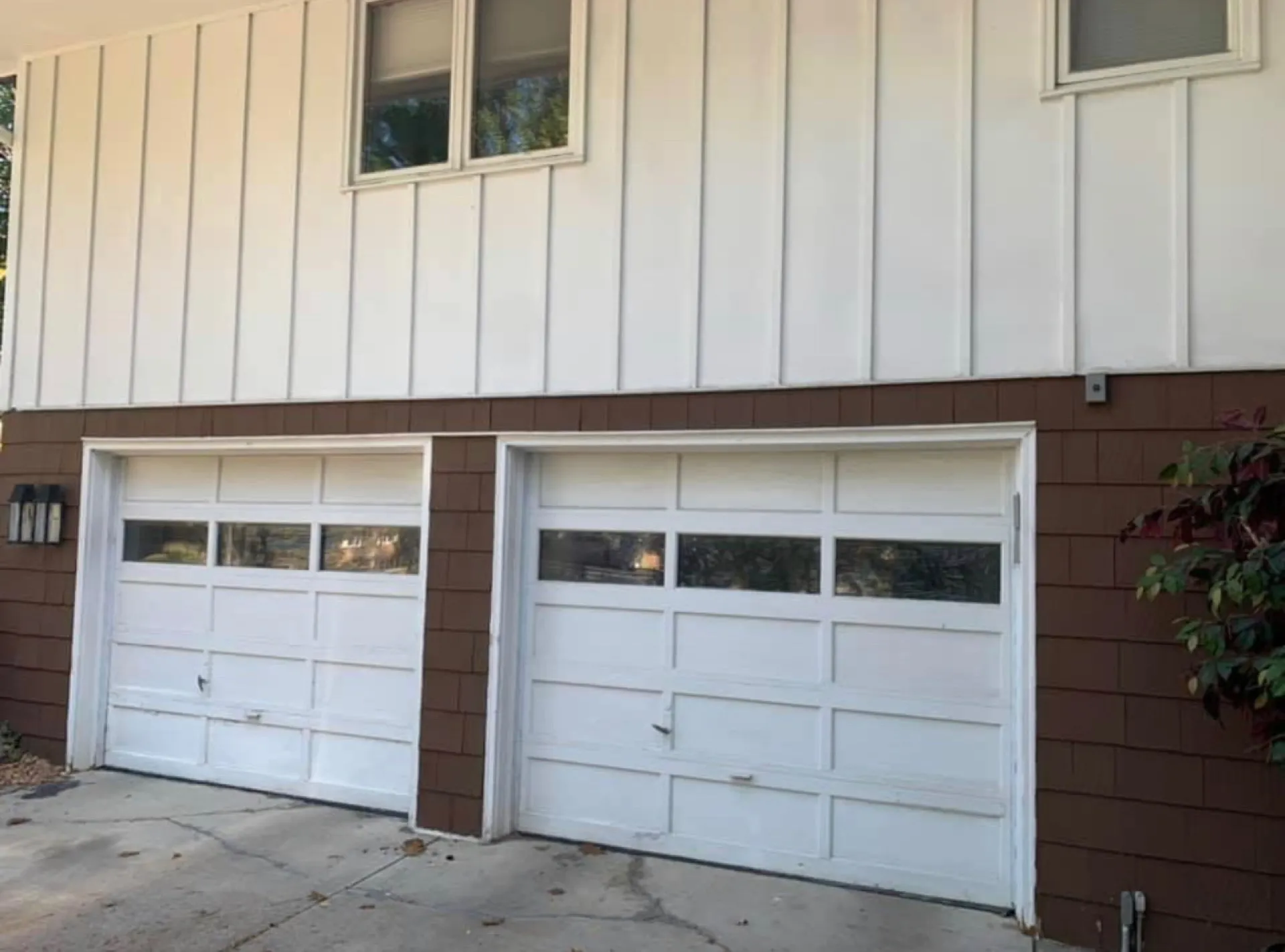 Two white carriage garage doors on a mid-century home