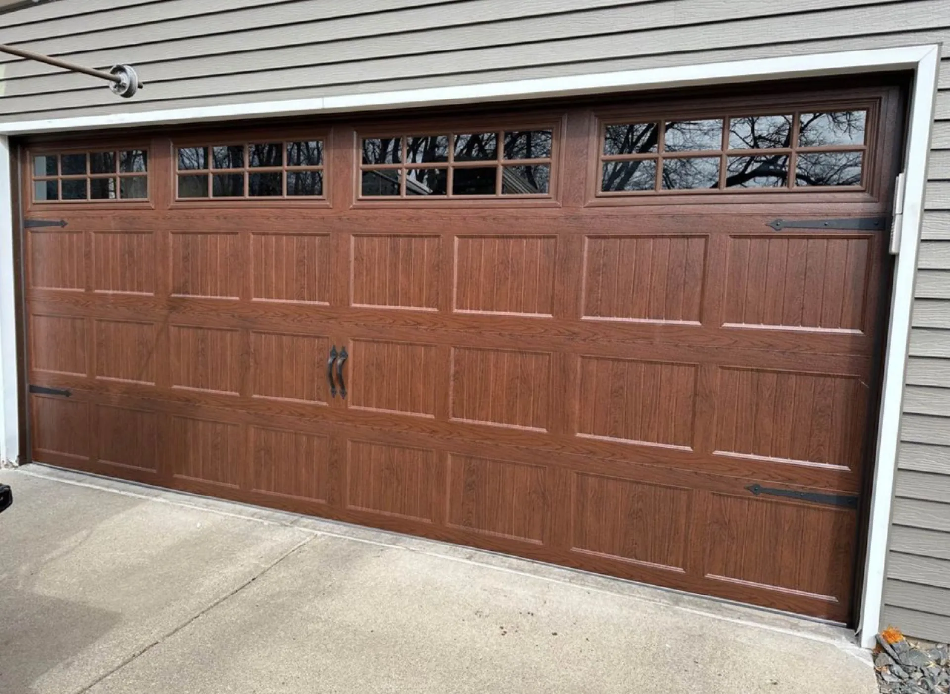 Warm wood-grain finish overhead door with iron carriage hardware